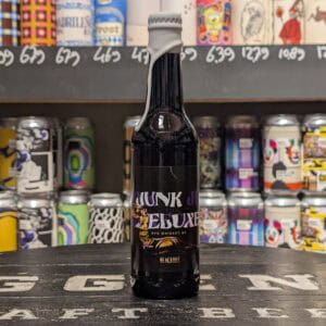Flinke fles met JUNK ELIJAH in slijterij Gils, kleurrijk assortiment op achtergrond.
