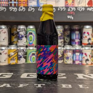 Klein bierflesje met kleurrijk, abstract label en gele dop op winkelvloer.
